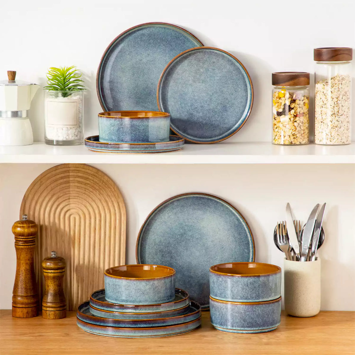 Onion 12-piece stoneware dinnerware stacked on white cabinet with storage jars, featuring reactive glaze in indigo and caramel tones