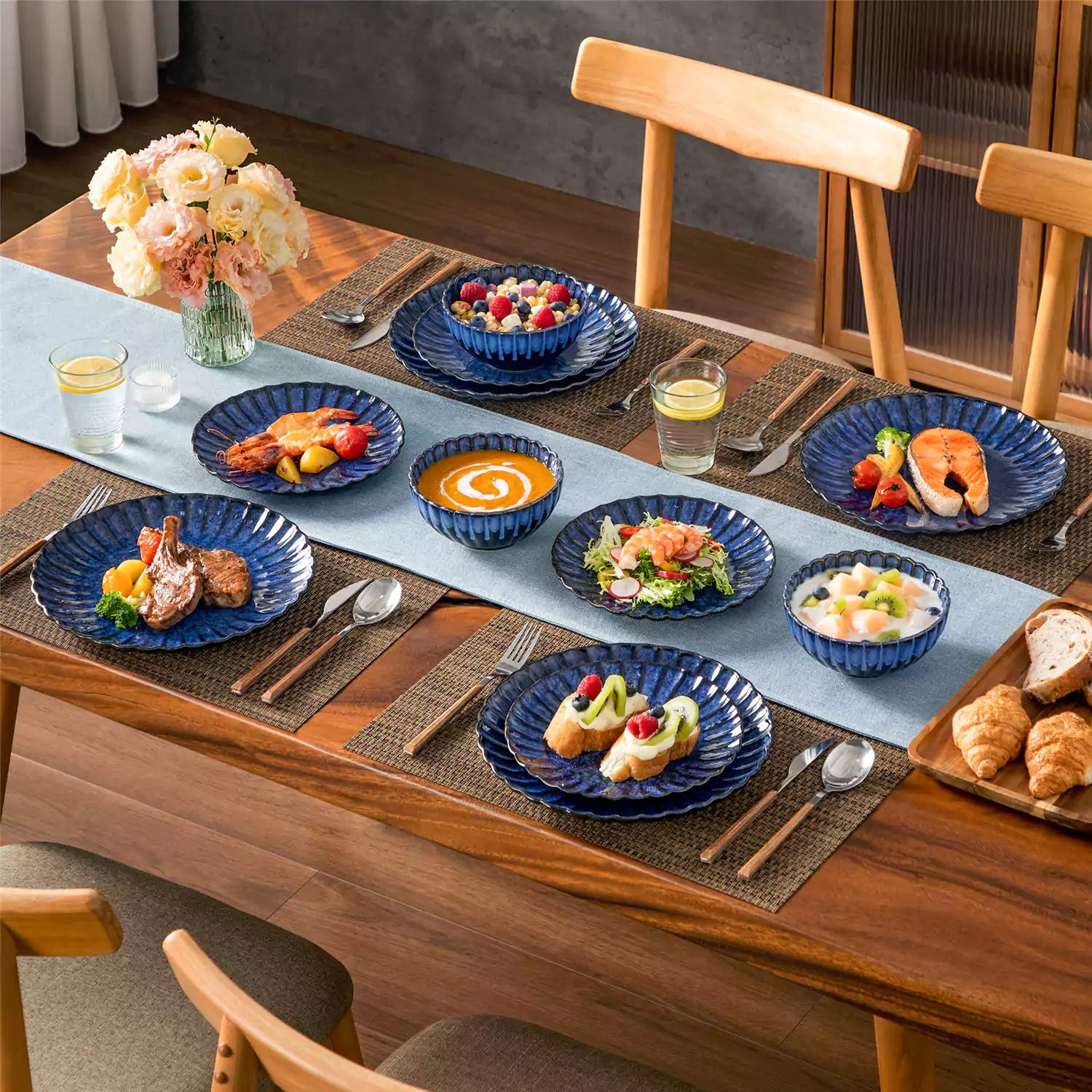 Blue reactive glaze stoneware bowls and plates from the Adonis 12 piece set with brown placemats and fresh flowers