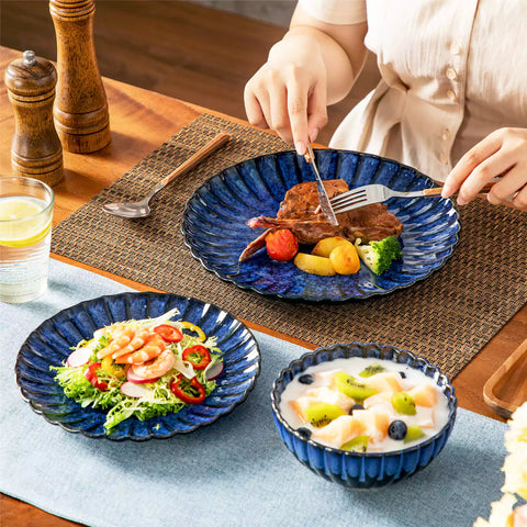 Blue reactive glaze stoneware bowls and plates from the Adonis 12 piece set with brown placemats and fresh flowers