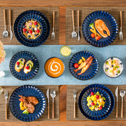 Adonis 18 piece reactive glaze dinnerware set in deep blue with ribbed bowls and plates on a dining table