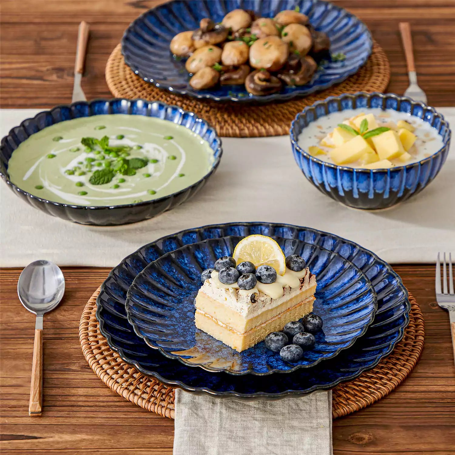 Adonis 16 piece reactive glaze dinnerware set in teal blue with pasta steak and fruit on a wooden dining table