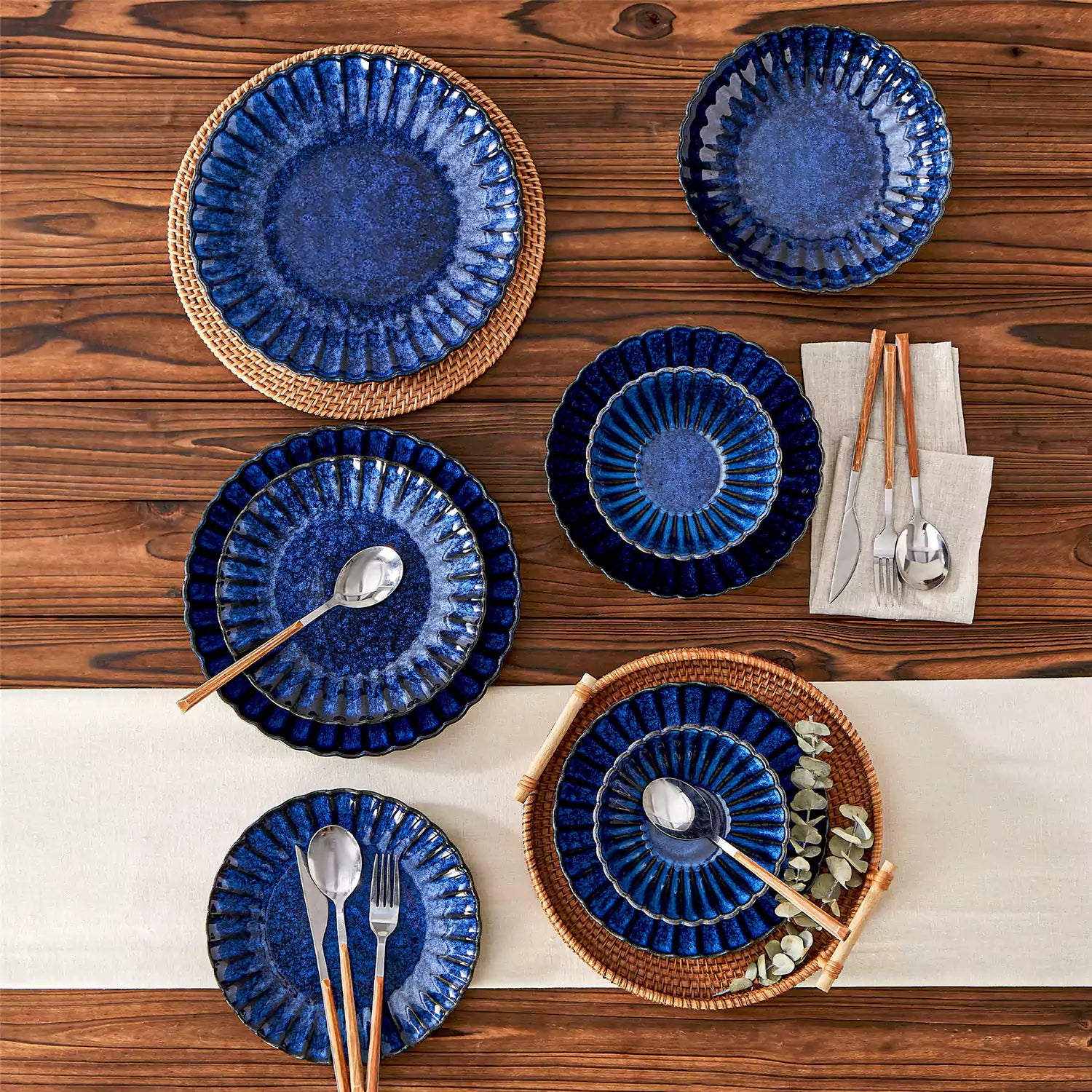 Adonis 16 piece reactive glaze dinnerware set in teal blue with pasta steak and fruit on a wooden dining table