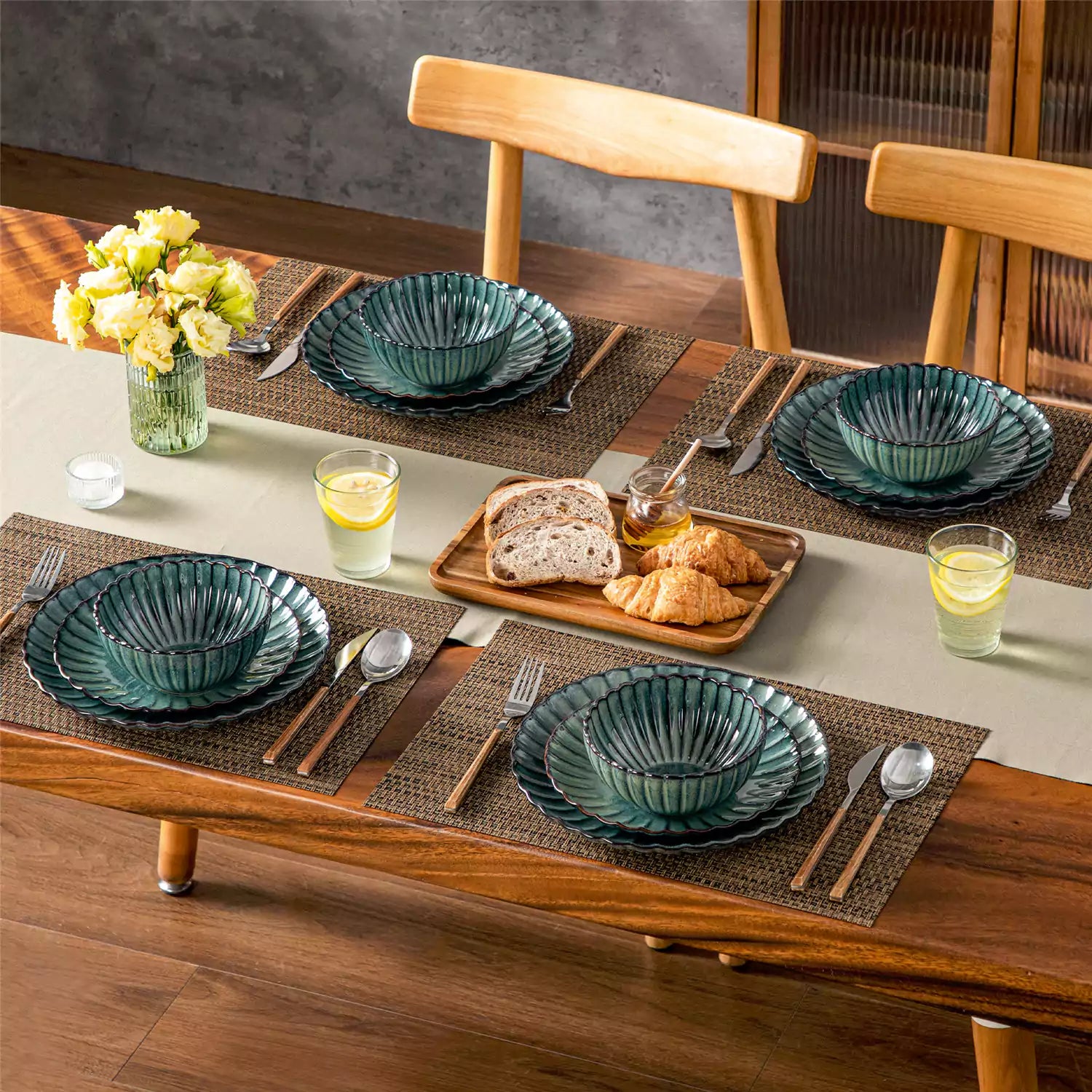 Green reactive glaze stoneware bowls and plates from the Adonis 12 piece set with brown placemats and fresh flowers