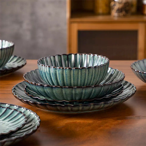 Farmhouse dining table set with Adonis teal green reactive glaze stoneware plates woven placemats and wooden chairs
