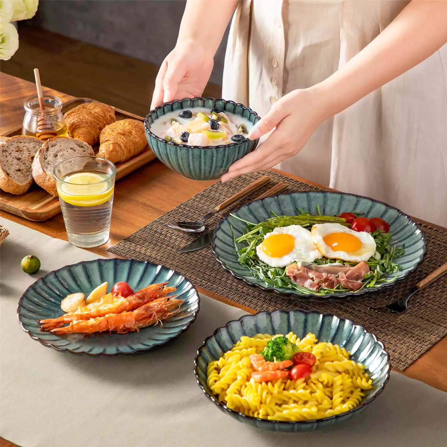 Farmhouse dining table set with Adonis teal green reactive glaze stoneware plates woven placemats and wooden chairs