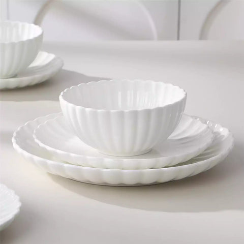 Bright modern dining room with Adonis white porcelain plates bowls white chairs and light wood accents