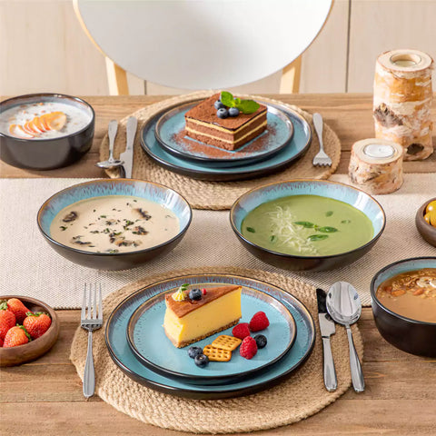 Assorted dishes with soup - dessert - and fruit salad on rustic wooden table - Amber 16-Piece blue stoneware dinnerware set with plates and bowls by vancasso