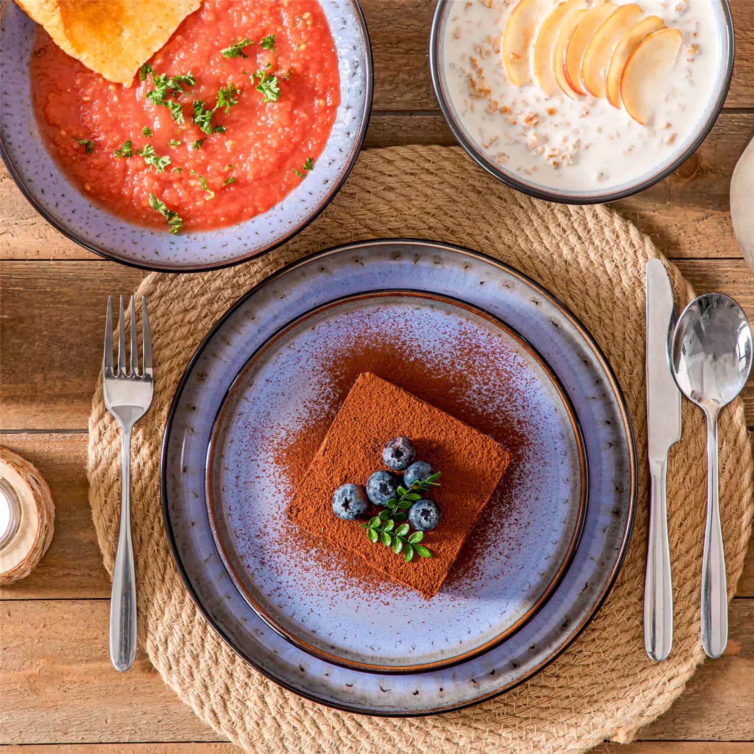 Assorted dishes with soup - dessert - and fruit salad on rustic wooden table - Amber 16-Piece violet stoneware dinnerware set with plates and bowls by vancasso
