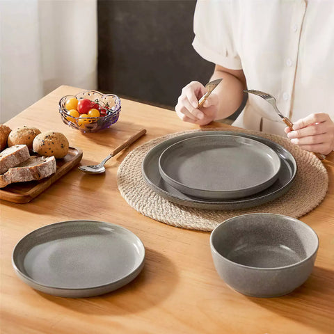 Brown stoneware plates and bowls with reactive glaze on farmhouse wooden table with woven placemats