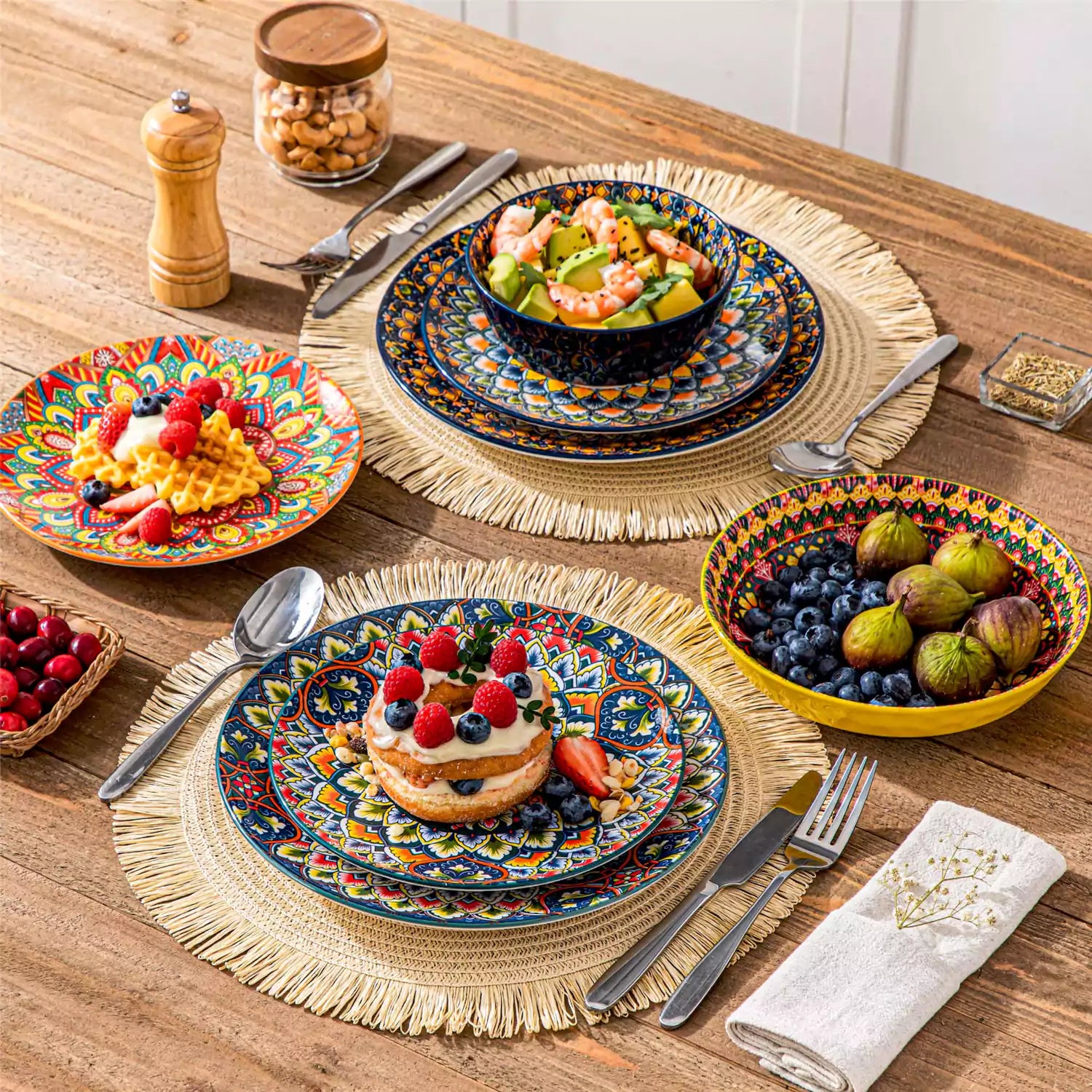 Lumi 24 piece porcelain dinnerware set with vibrant patterns stacked on a wooden table with colorful placemats and assorted dishes