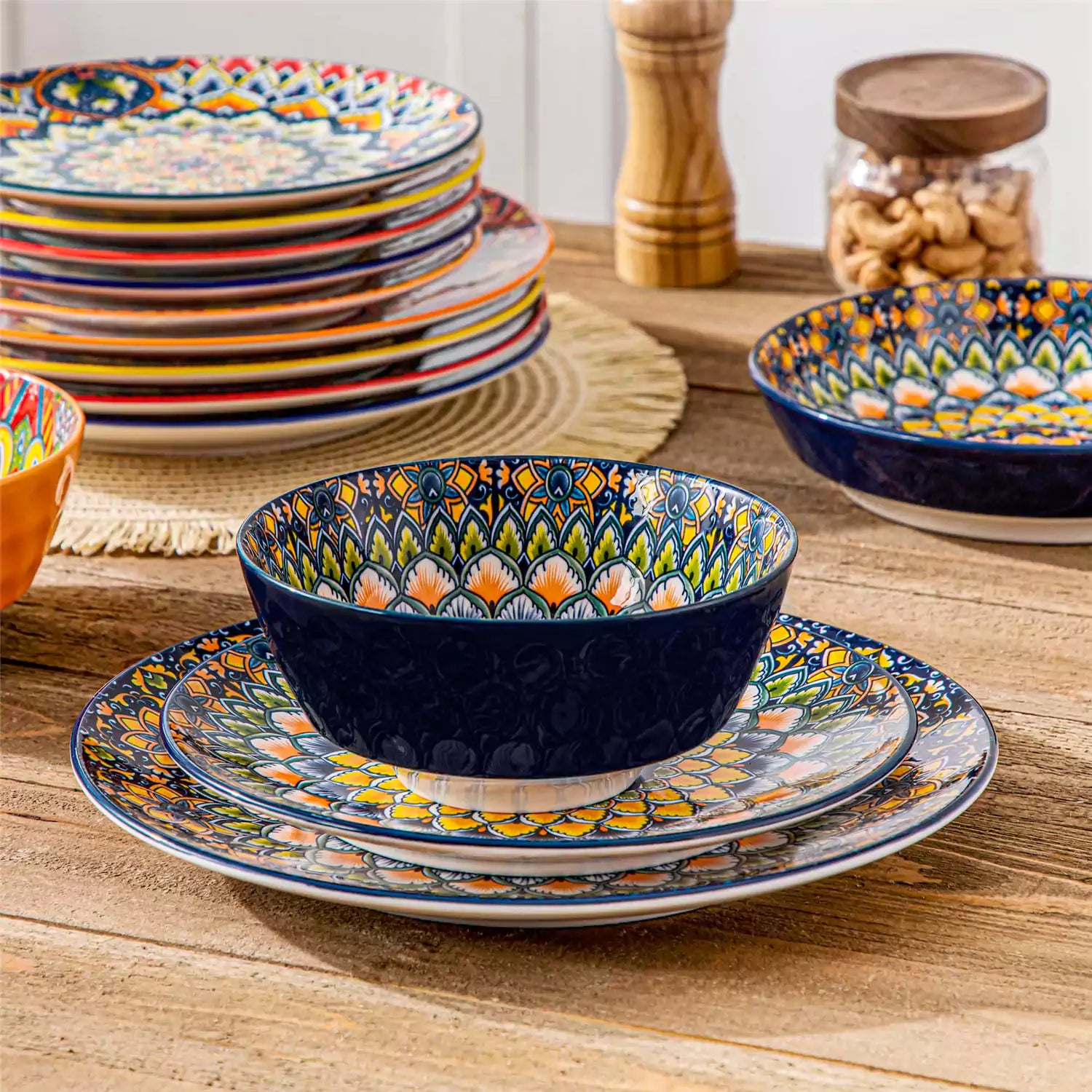 Lumi 24 piece porcelain dinnerware set with vibrant patterns stacked on a wooden table with colorful placemats and assorted dishes