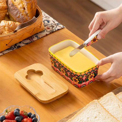 Lumi lemon yellow porcelain butter dish with lid in vibrant Bohemian pattern on a wooden table