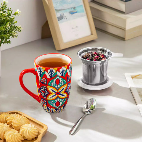 Lumi flame red porcelain tea mug with infuser and lid featuring vibrant Bohemian pattern on a wooden desk with laptop and plant