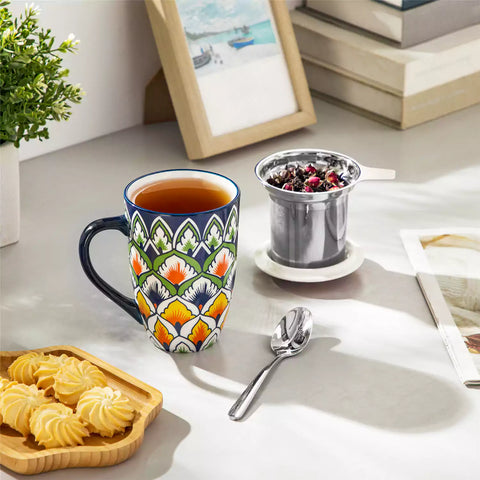 Lumi hunter green porcelain tea mug with infuser and lid featuring vibrant Bohemian pattern on a wooden desk with laptop and plant