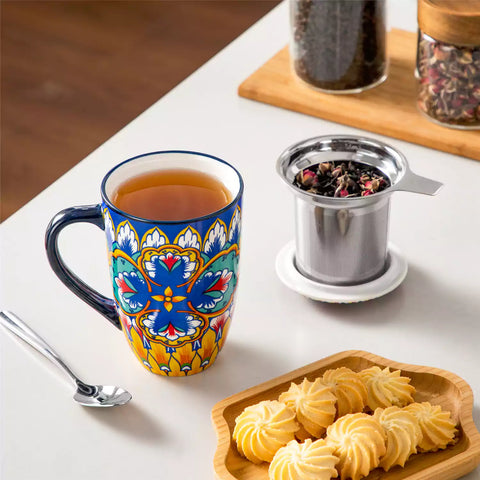 Lumi vibrant blue porcelain tea mug with infuser and lid featuring vibrant Bohemian pattern on a wooden desk with laptop and plant
