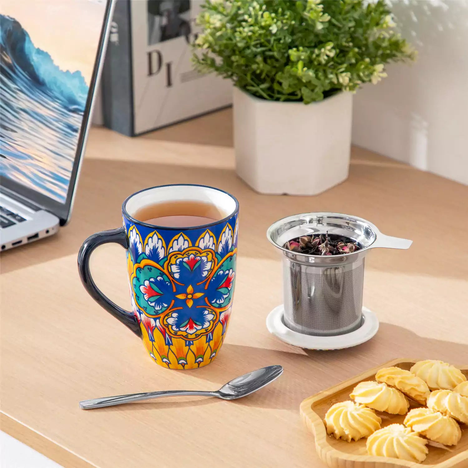 Lumi vibrant blue porcelain tea mug with infuser and lid featuring vibrant Bohemian pattern on a wooden desk with laptop and plant