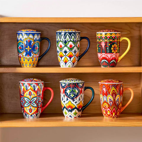 Lumi bold orange porcelain tea mug with infuser and lid featuring vibrant Bohemian pattern on a wooden desk with laptop and plant