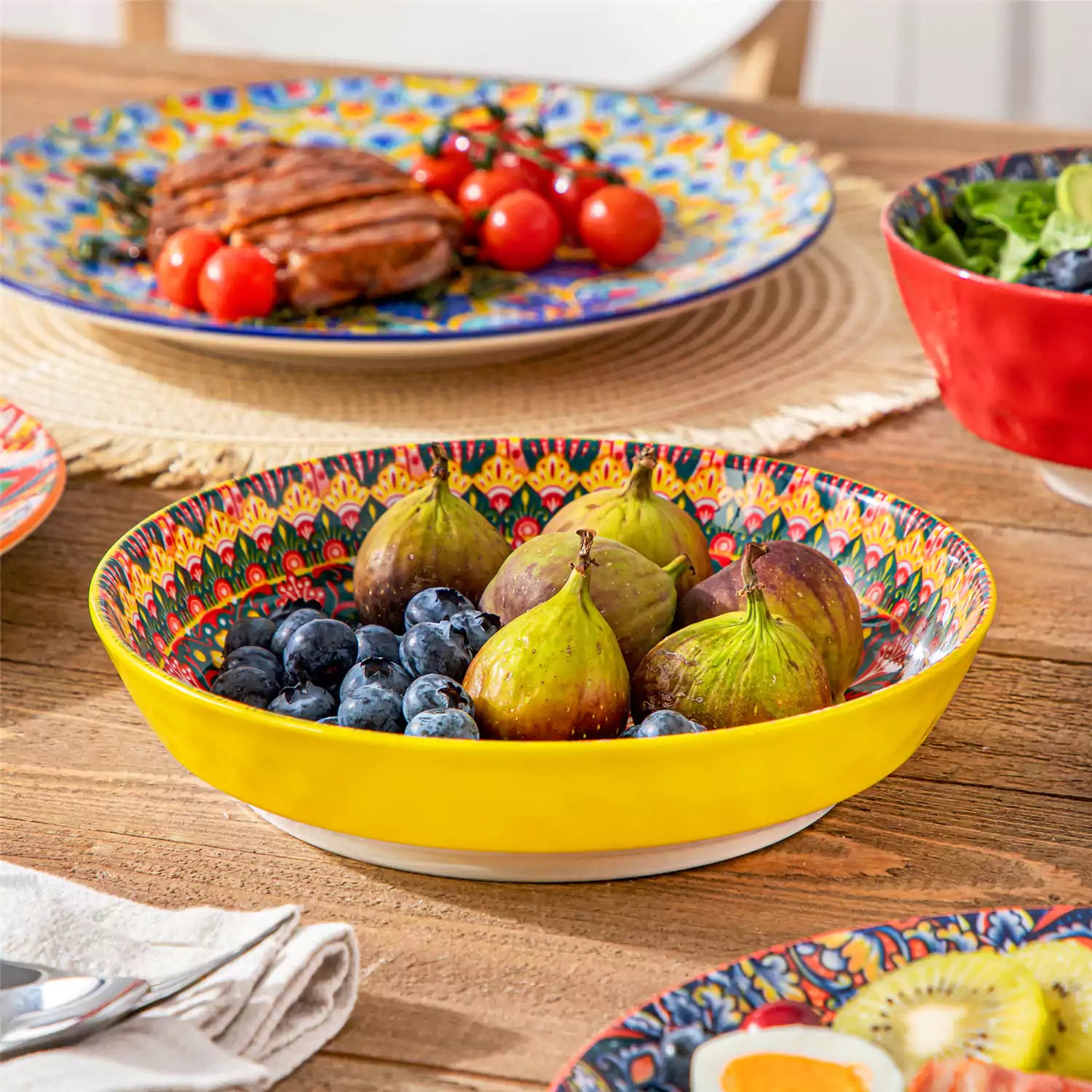 Bohemian Lumi 16 piece porcelain dinnerware set with colorful patterned plates and diamond-embossed bowls on a wooden table with assorted food and cutlery