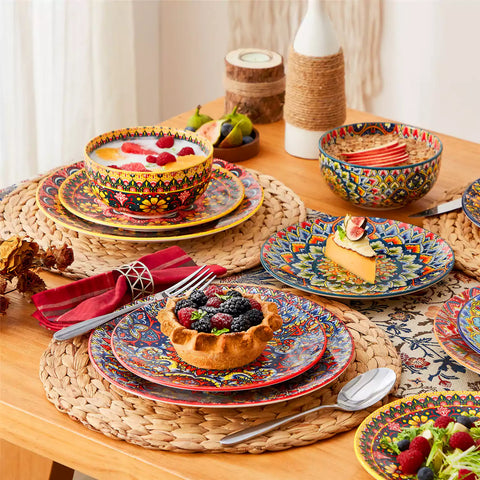 Lumi 18-piece Bohemian dinnerware set for six on a wooden table with colorful plates bowls and silverware in a playful Boho style