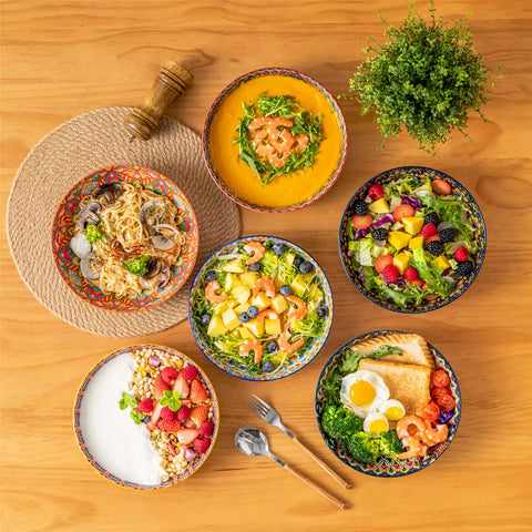 Vibrant Lumi porcelain pasta bowls filled with fruit salad pumpkin soup and pasta on a wooden dining table