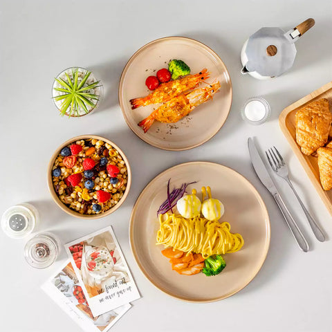 A rustic breakfast spread featuring a plate of meat with vegetables - waffles topped with fruit - and assorted pastries on a white table - complemented by caramel stoneware dinnerware
