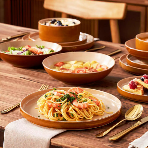 Assorted family dinnerware on wooden table brown stoneware soup bowl pasta with shrimp fruit tart and bread perfect for everyday meals