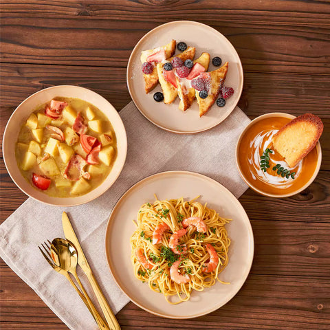 Assorted family dinnerware on wooden table brown stoneware soup bowl pasta with shrimp fruit tart and bread perfect for everyday meals