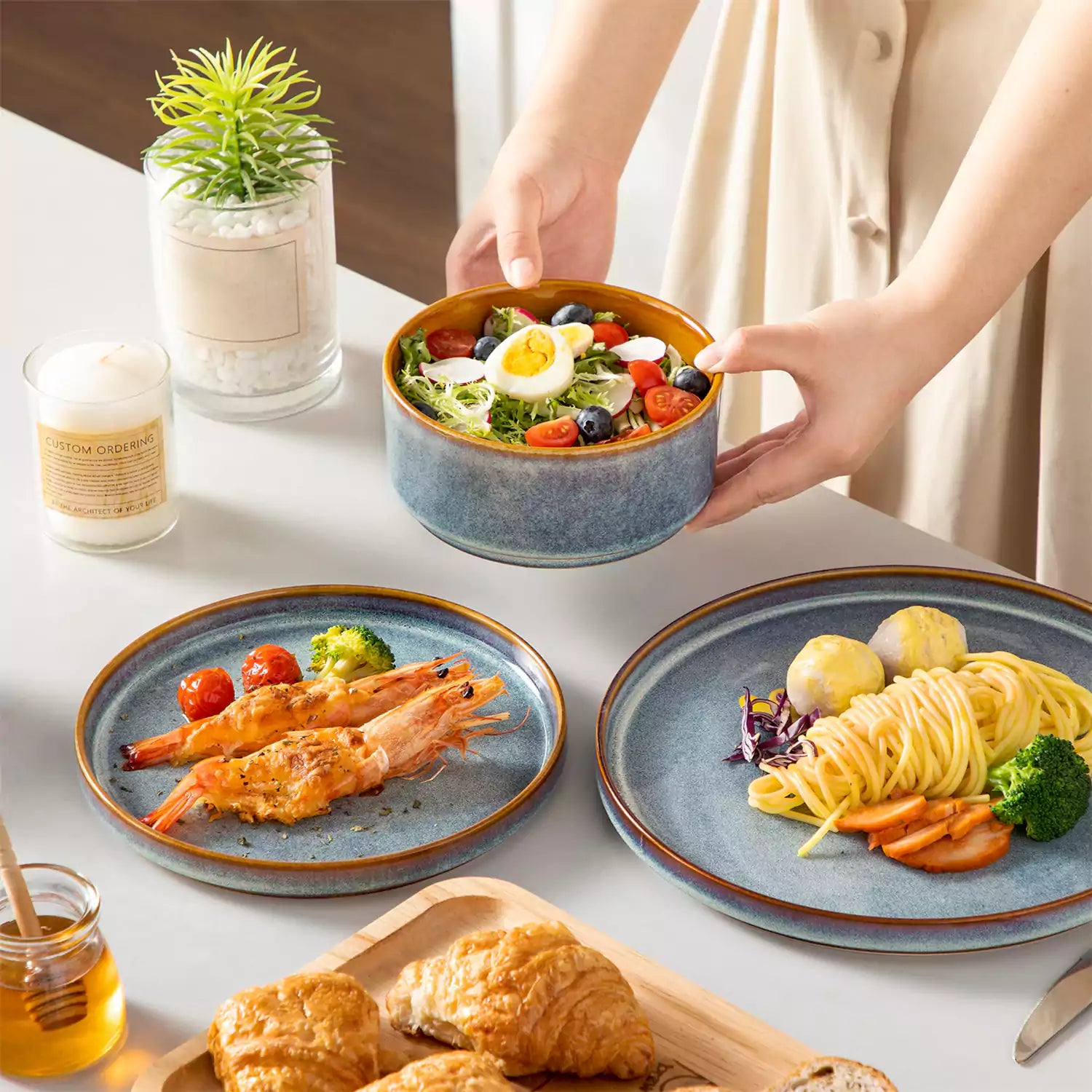 A rustic breakfast spread featuring a plate of meat with vegetables - waffles topped with fruit - and assorted pastries on a white table - complemented by blue stoneware dinnerware