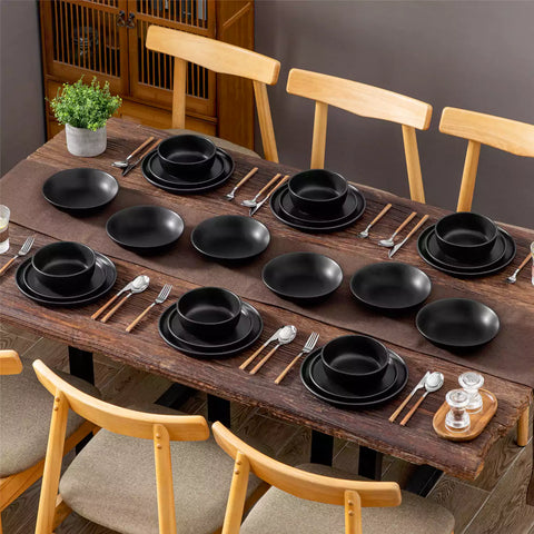 A matte black 24-piece stoneware dinnerware set from the Playa collection by vancasso - adding a modern flair with plates and bowls for 6 people