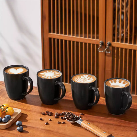 Playa set of four black stoneware mugs and a classic Moka pot on a wooden tray with a morning brew beside fresh pastries and coffee beans