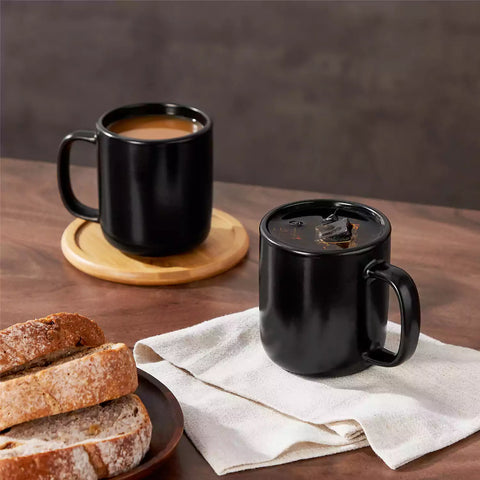 Playa 12oz stoneware mug in solid matte black on a rustic wooden surface for a moody coffee break with spoon and scattered beans