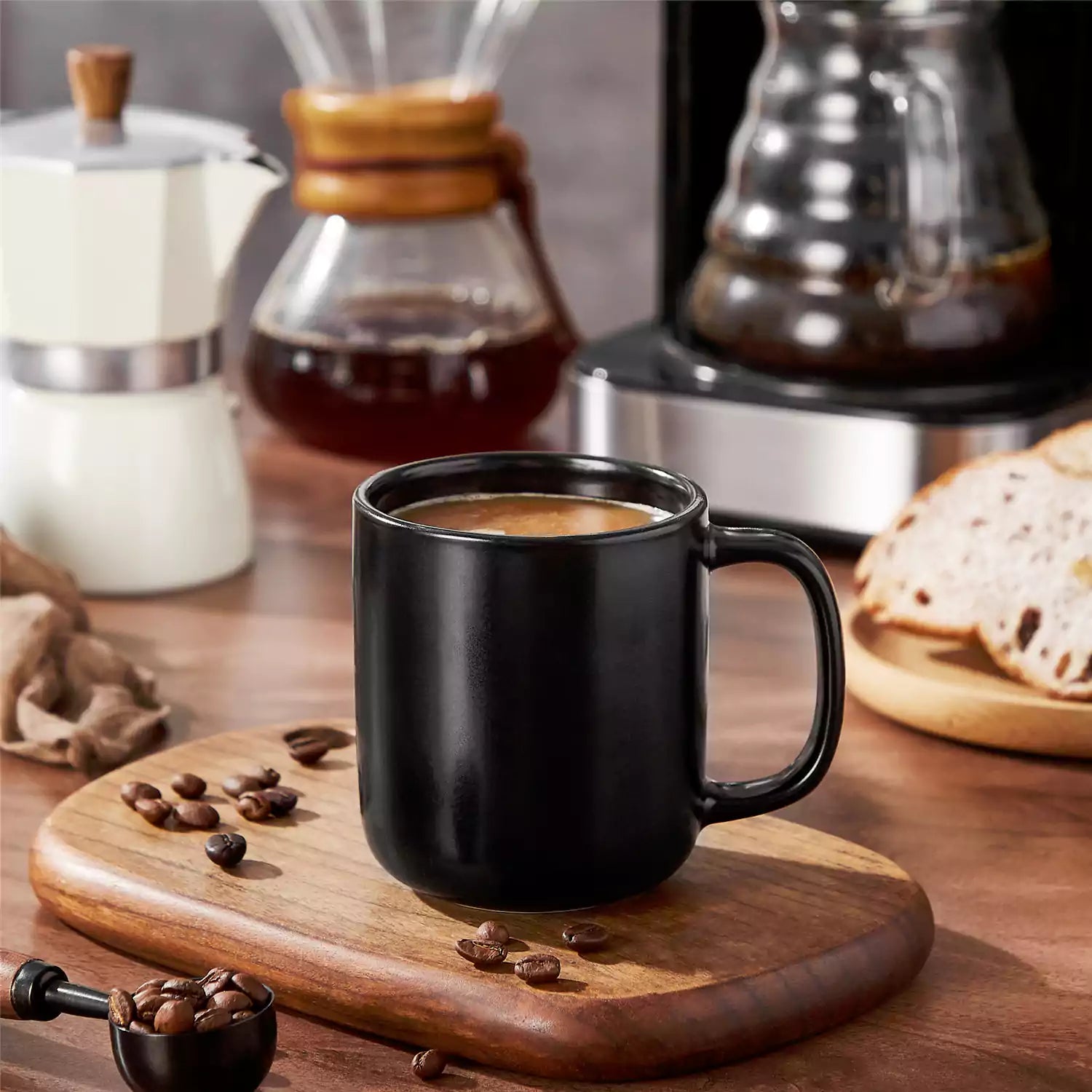 Playa 12oz stoneware mug in solid matte black on a rustic wooden surface for a moody coffee break with spoon and scattered beans