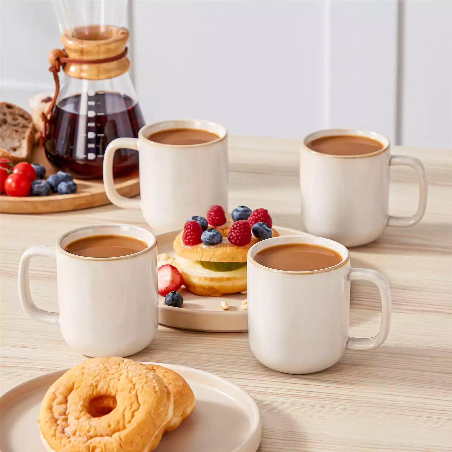 Playa 12oz stoneware mugs in glossy beige reactive glaze on a rustic wooden table for a cozy breakfast with fresh coffee pastries and berries