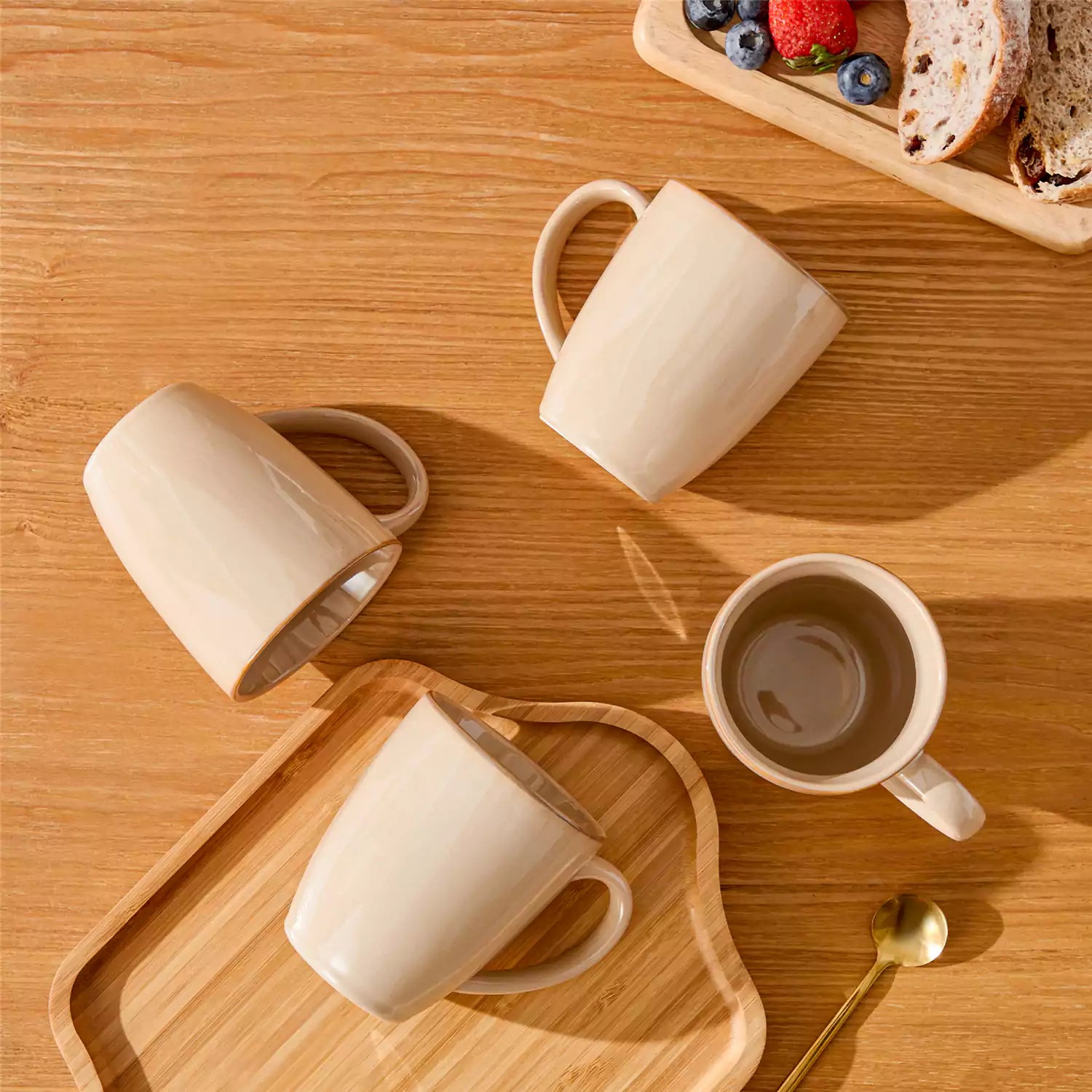 Playa set of four brown reactive glaze stoneware mugs on a wooden tray with a flat white and black coffee beside fresh croissants and berries