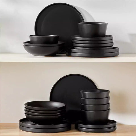 Modern black stoneware bowl and plate set displayed on a marble countertop - with a fresh salad blurred in the background - vancasso