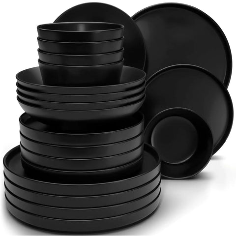 Modern black stoneware bowl and plate set displayed on a marble countertop - with a fresh salad blurred in the background - vancasso