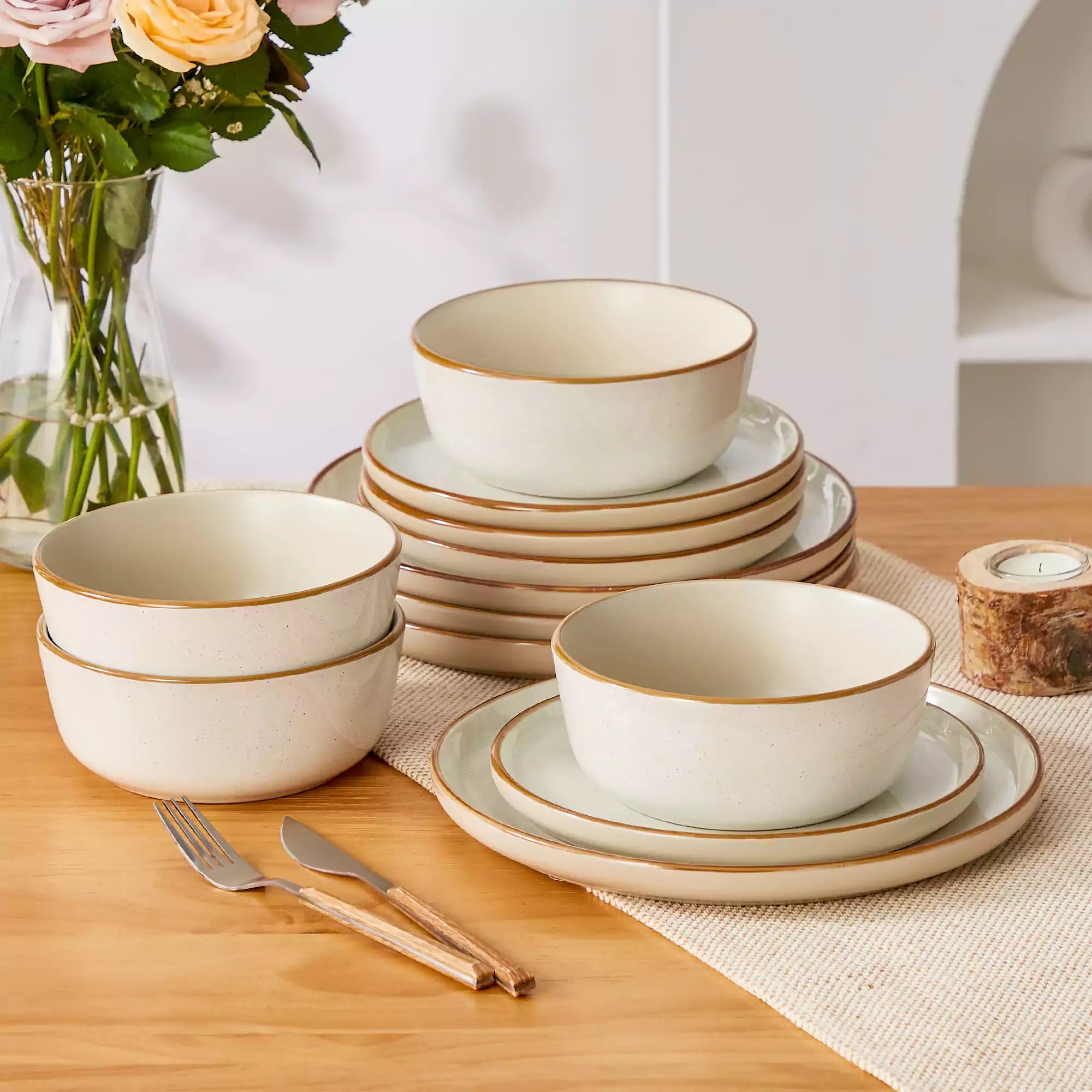 Beige rustic stoneware dinnerware set with speckled - lipped-edge plates and bowls on a dining table with flowers and cutlery in a cozy modern kitchen-vancasso