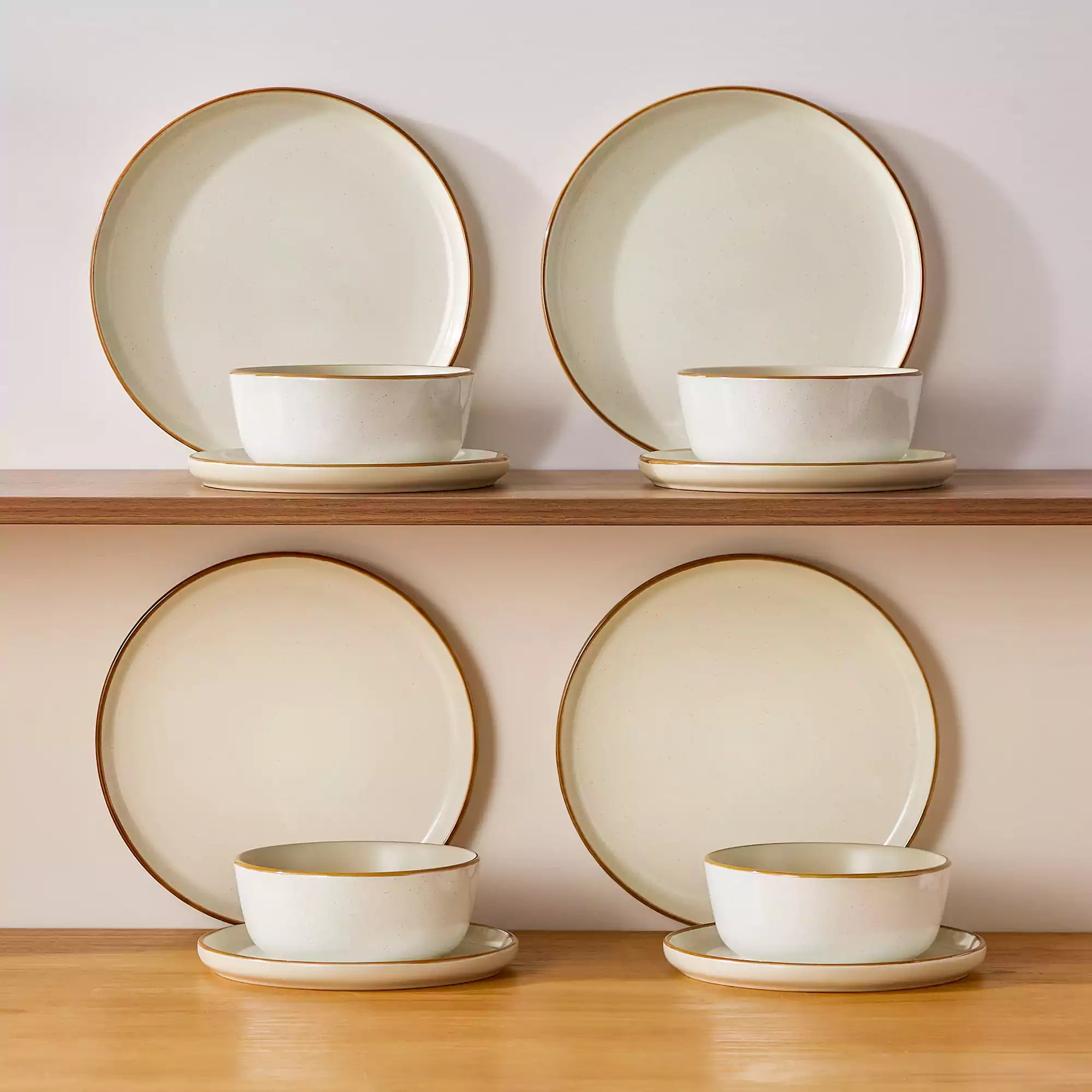 Beige rustic stoneware dinnerware set with speckled - lipped-edge plates and bowls on a dining table with flowers and cutlery in a cozy modern kitchen-vancasso