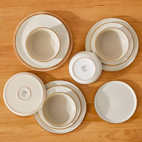 Beige rustic stoneware dinnerware set with speckled - lipped-edge plates and bowls on a dining table with flowers and cutlery in a cozy modern kitchen-vancasso