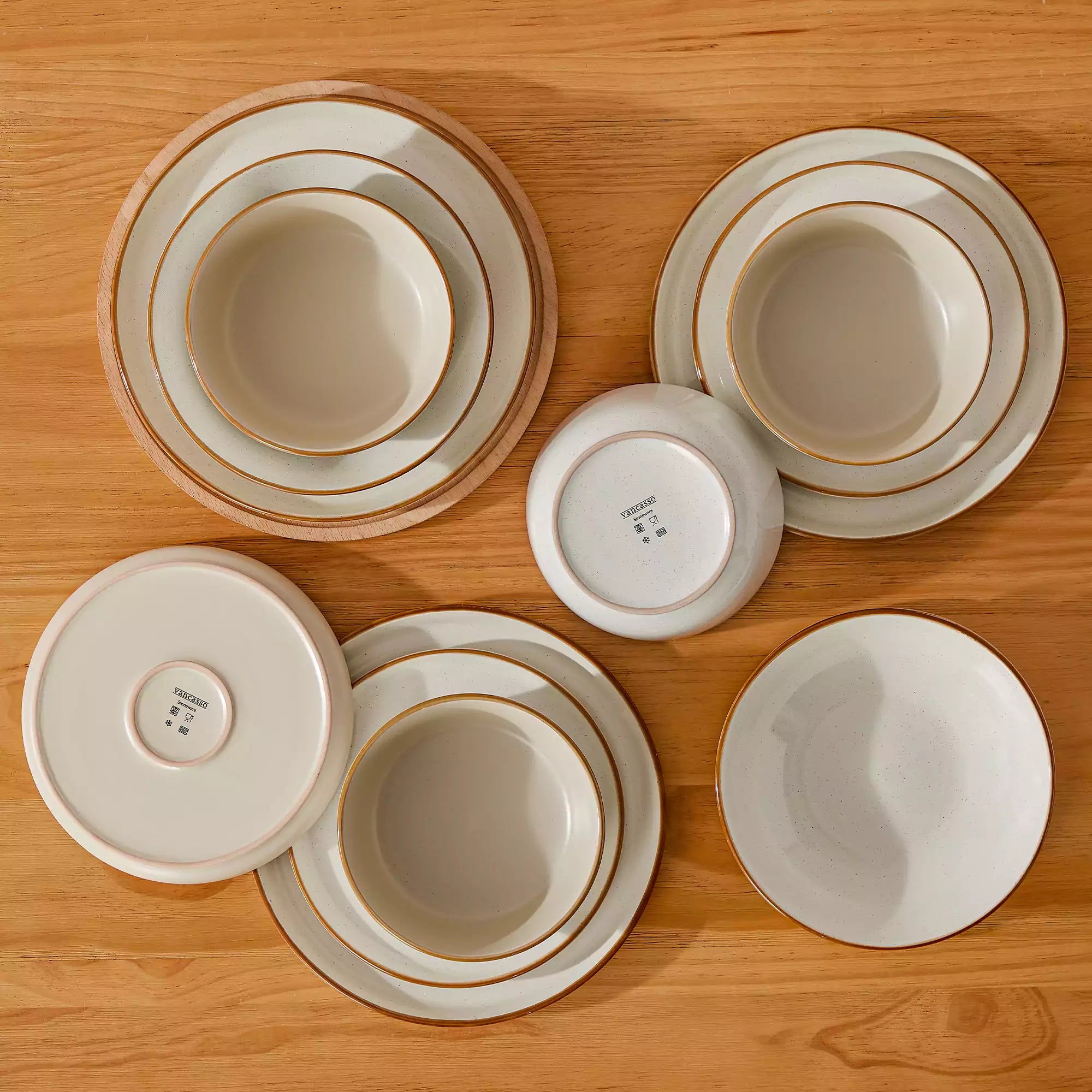 Rustic beige speckled stoneware dinnerware set with lipped-edge plates and bowls arranged on a sunlit modern dining table-vancasso