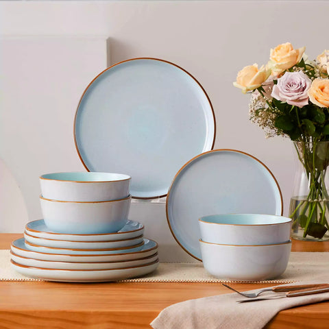 Blue rustic stoneware dinnerware set with speckled - lipped-edge plates and bowls on a dining table with flowers and cutlery in a cozy modern kitchen-vancasso