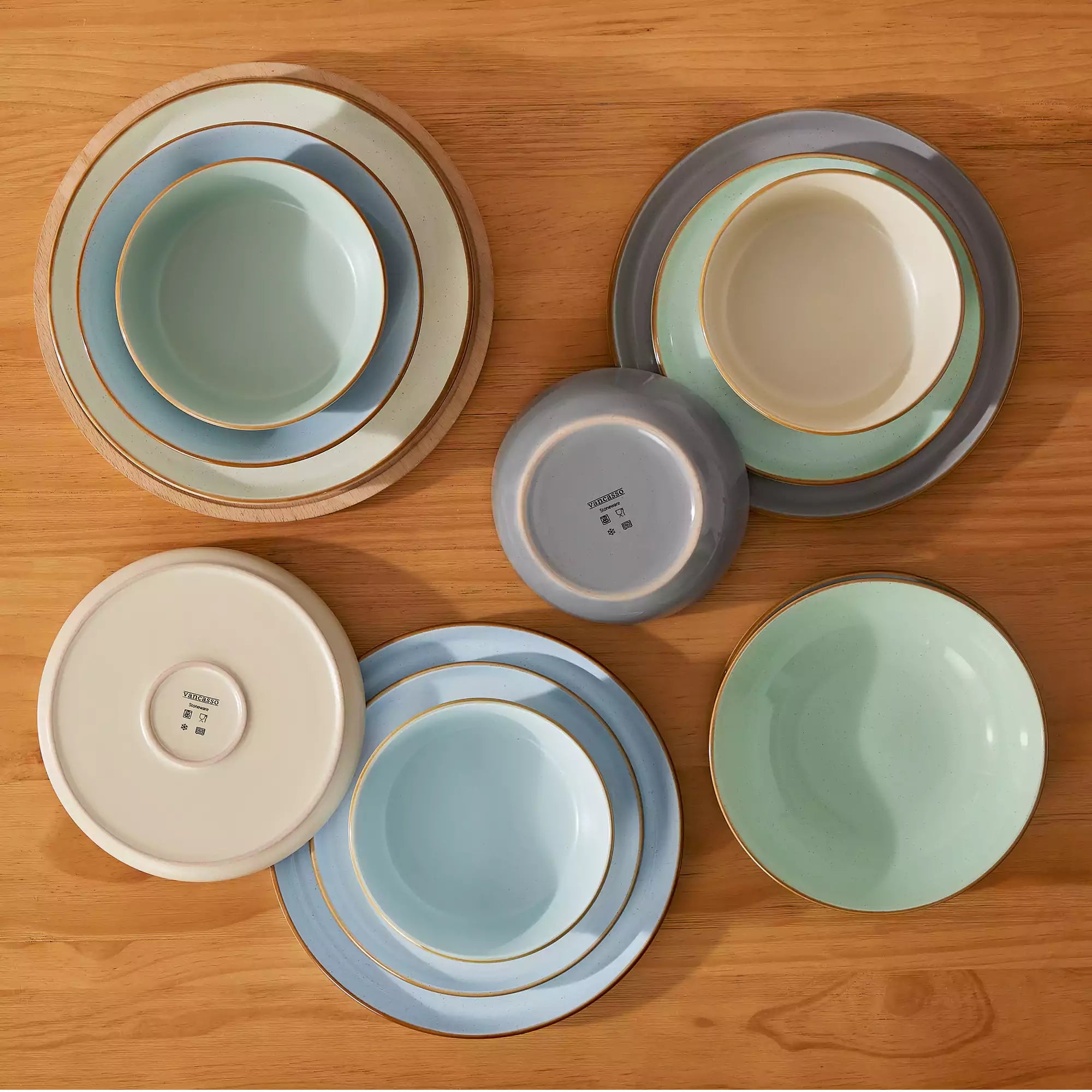 Rustic assorted speckled stoneware dinnerware set with lipped-edge plates and bowls arranged on a sunlit modern dining table-vancasso