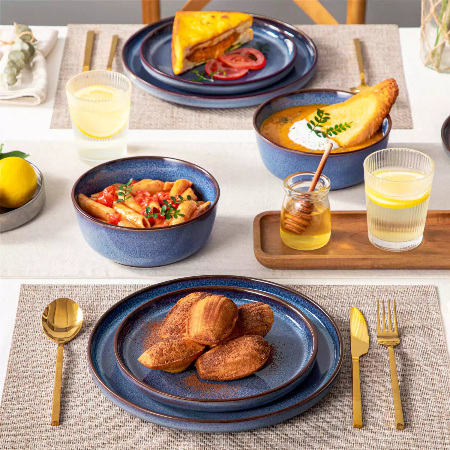 Sata blue stoneware 12 piece dinnerware set with dinner plates salad plates and cereal bowls styled with gold cutlery on textured surface farmhouse reactive glaze lipped edge service for 4