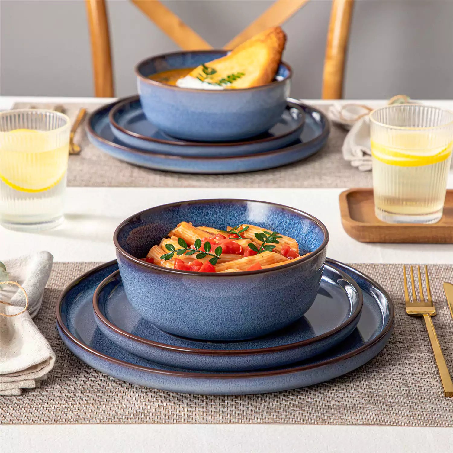 Sata blue stoneware 12 piece dinnerware set with dinner plates salad plates and cereal bowls styled with gold cutlery on textured surface farmhouse reactive glaze lipped edge service for 4