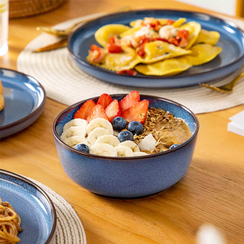 Sata blue stoneware 18 piece dinnerware set with dinner plates salad plates and cereal bowls styled on a wooden table with diverse meal setup farmhouse reactive glaze lipped edge service for 6
