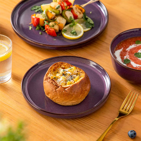 Sata purple stoneware 18 piece dinnerware set with dinner plates salad plates and cereal bowls styled on a wooden table with diverse meal setup farmhouse reactive glaze lipped edge service for 6