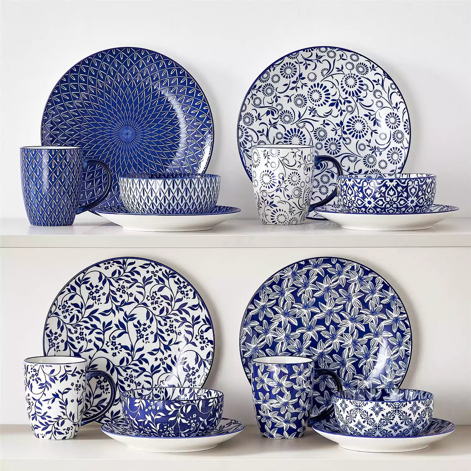 Selene 16-piece porcelain set in indigo patterns - showcasing plates - bowls - and mugs beautifully styled with vibrant meals on a rustic wooden table