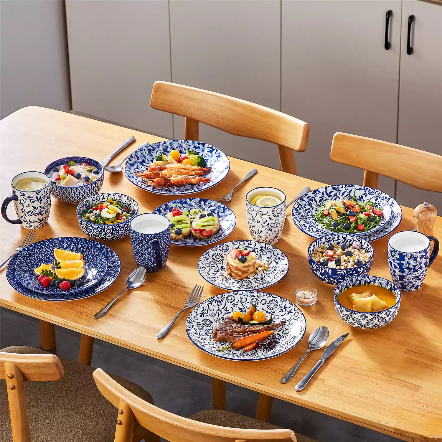 Selene 16-piece porcelain set in indigo patterns - showcasing plates - bowls - and mugs beautifully styled with vibrant meals on a rustic wooden table