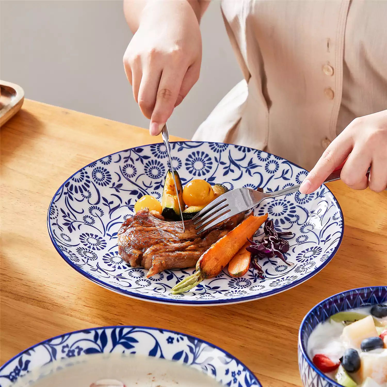 Selene 16-piece porcelain set in indigo patterns - showcasing plates - bowls - and mugs beautifully styled with vibrant meals on a rustic wooden table