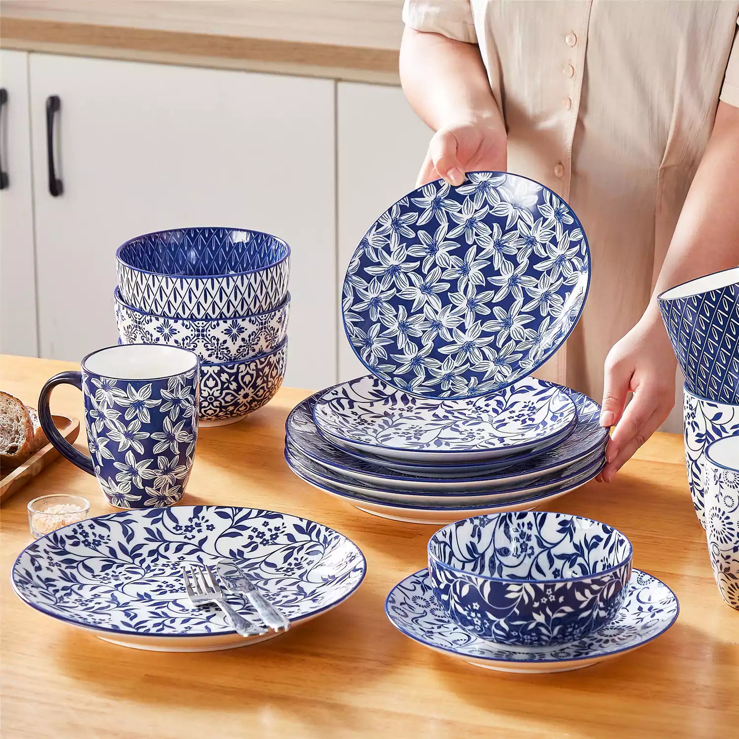 Selene 16-piece porcelain set in indigo patterns - showcasing plates - bowls - and mugs beautifully styled with vibrant meals on a rustic wooden table